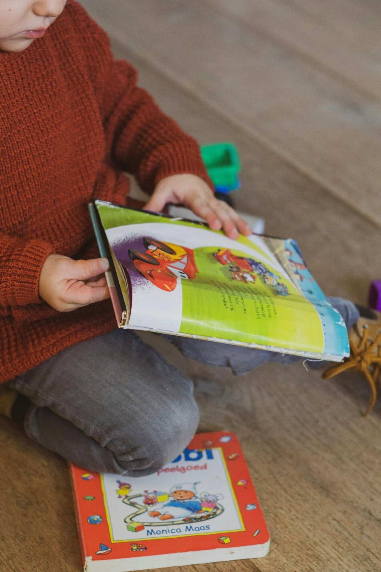 Toddler holding a storybook, showing early curiosity about reading